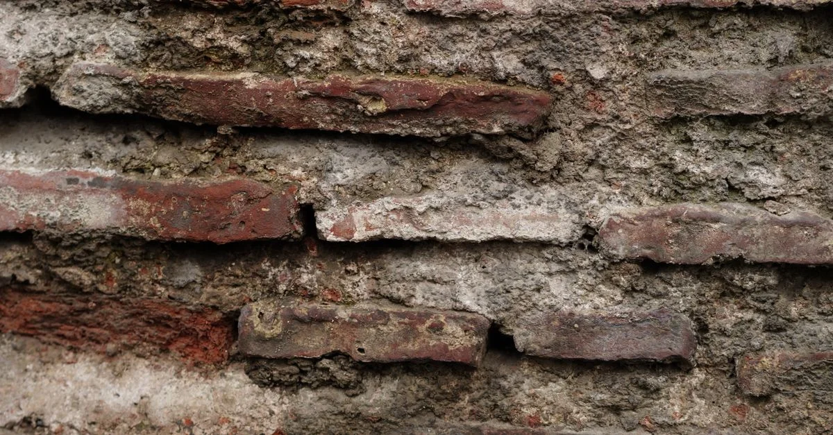Vue détaillée d'un mur de briques ancien et texturé montrant les effets des intempéries.